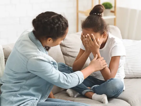 Adult offering comfort and support to an upset child during a conversation about challenges related to EBSA.