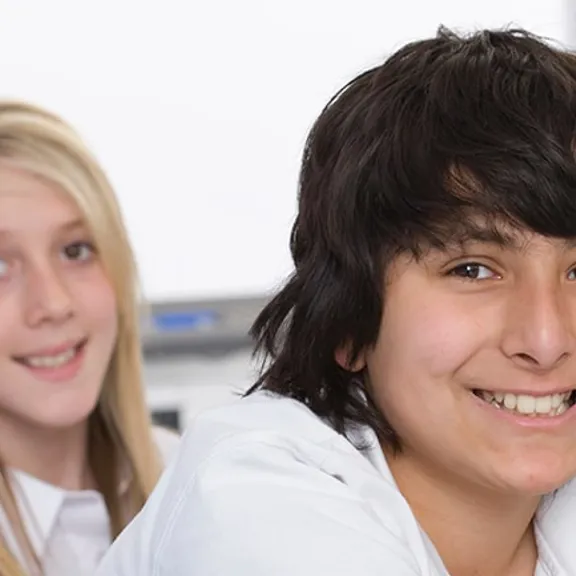 3 teenage students who have been working on computers looking at the camera.