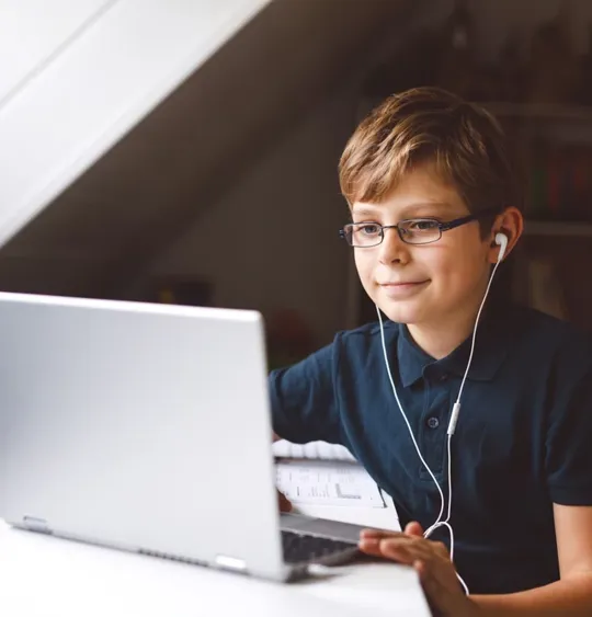 Young boy on laptop, with earphones in.