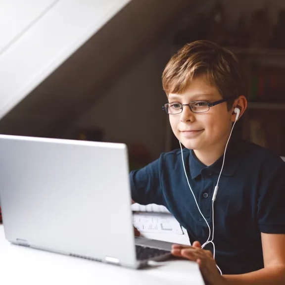 Young boy on laptop, with earphones in.