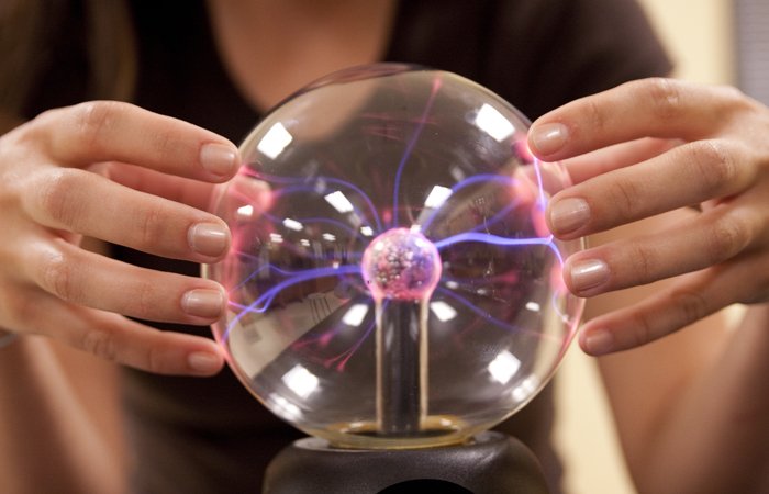 Student exploring plasma globe for A Level Physics, illustrating learning