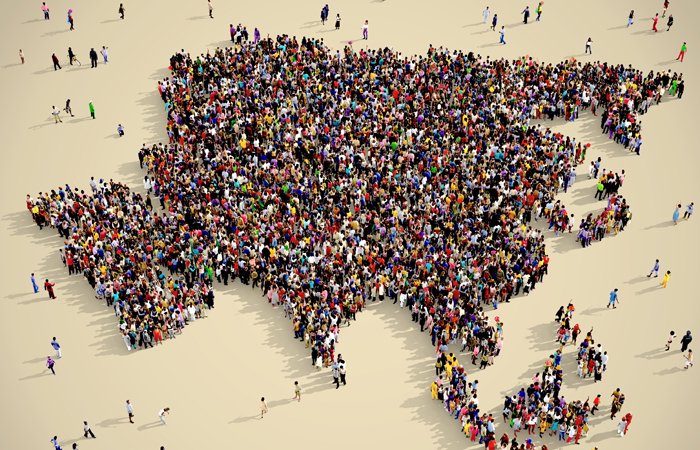 A group of people stood in a large cluster resembling a country, or mass of land. 