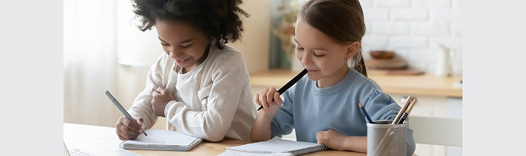 Two young girls writing together. 