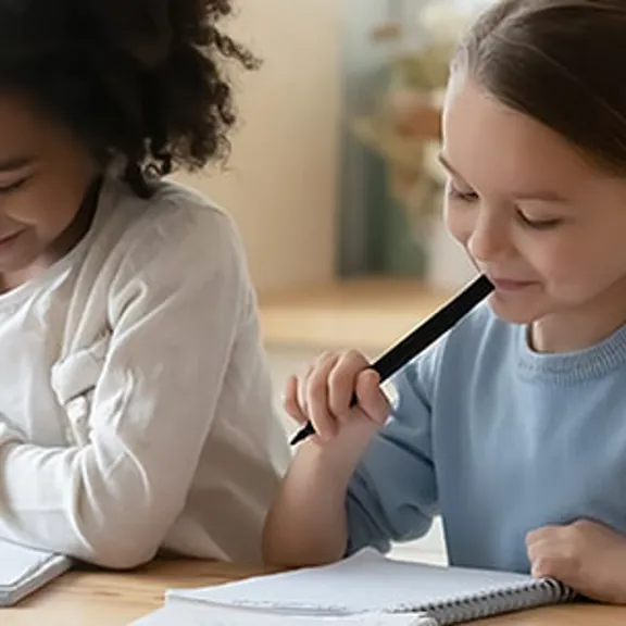 Two young girls writing together.