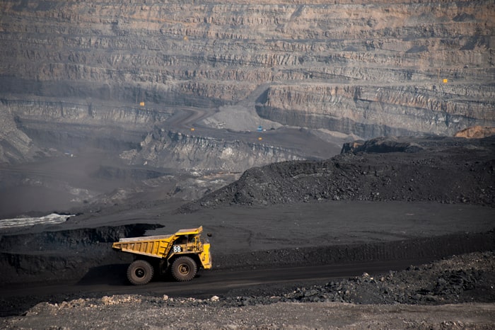 A large construction vehicle inside a giant stone quarry. 