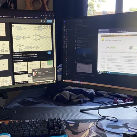 A desk with two large computer monitors displaying educational content, a keyboard, and a mousepad, indicating an organised study space.