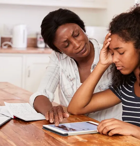 Mother helping teenage daughter with her studies, whilst she faces a moment of distress from anxiety.