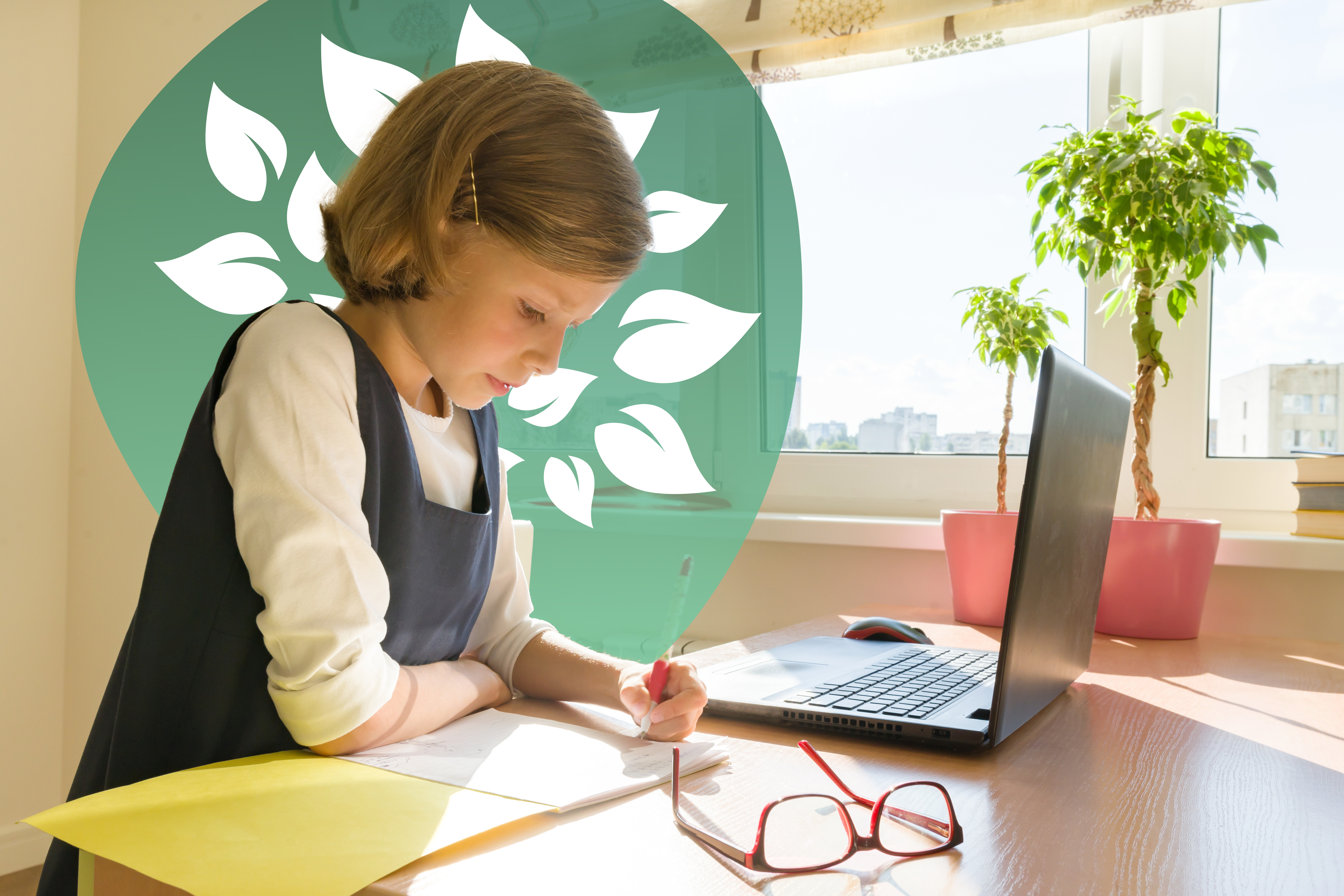 Young girl concentrating on her schoolwork, writing in a notebook at her desk during a homeschooling session with a laptop nearby.