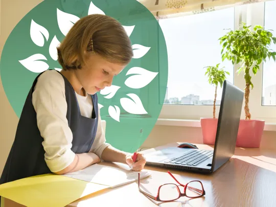 Young girl concentrating on her schoolwork, writing in a notebook at her desk during a homeschooling session with a laptop nearby.