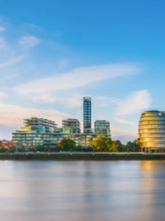 Sunlit view of Tower Bridge and the London skyline, featuring The Shard and city buildings along the Thames.