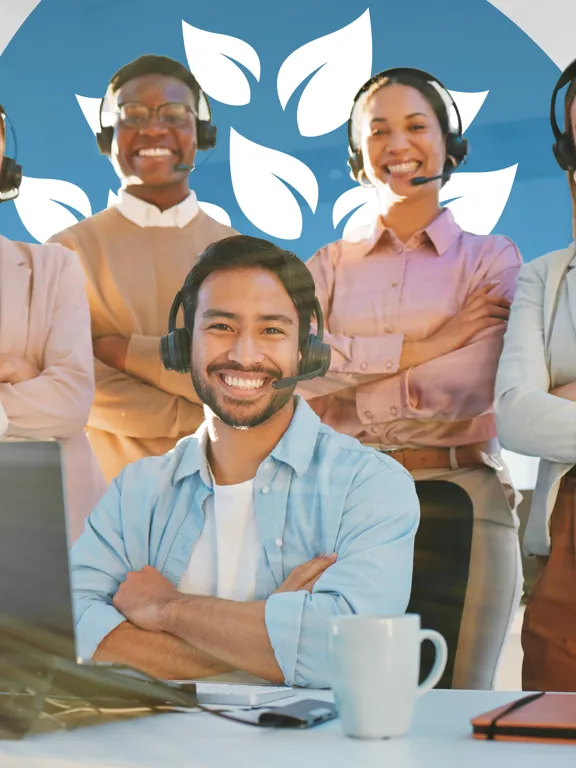 Five smiling customer service representatives wearing headsets, standing around a desk with a laptop, looking at the camera.