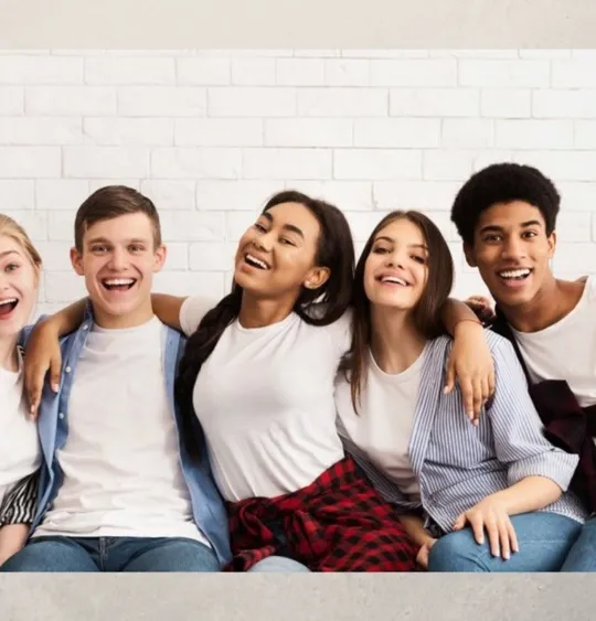 A Level age students sat together arm in arm, smiling.