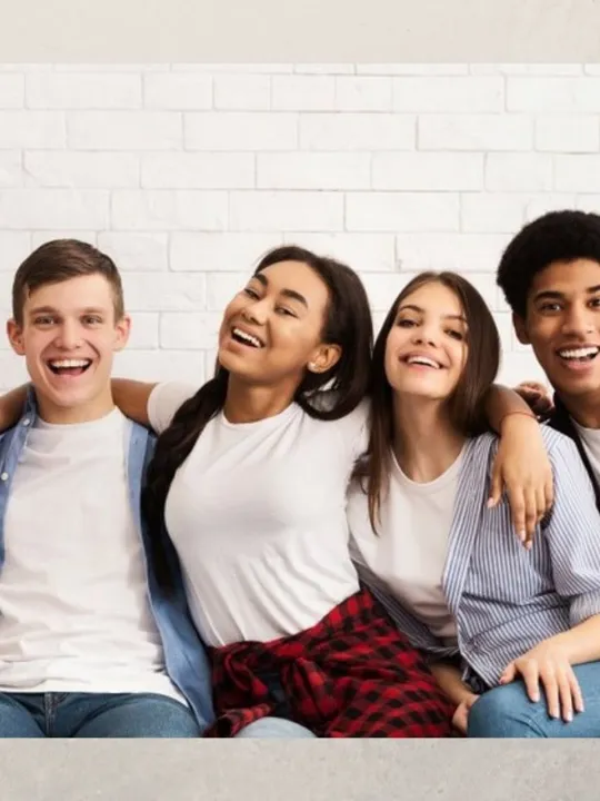 A Level age students sat together arm in arm, smiling.