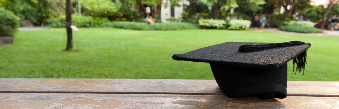 A photograph of a graduation mortarboard on a table next to a field.