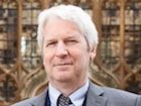 A close-up photograph of Lee Wilcock, who joined Wolsey Hall Oxford as Principal in 2009. Lee has short white hair and is wearing a suit. He is looking at the camera.