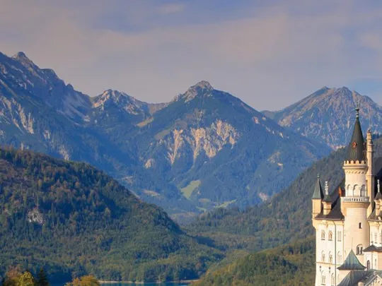 Neuschwanstein Castle set against a backdrop of alpine mountains and forests in Bavaria, Germany.