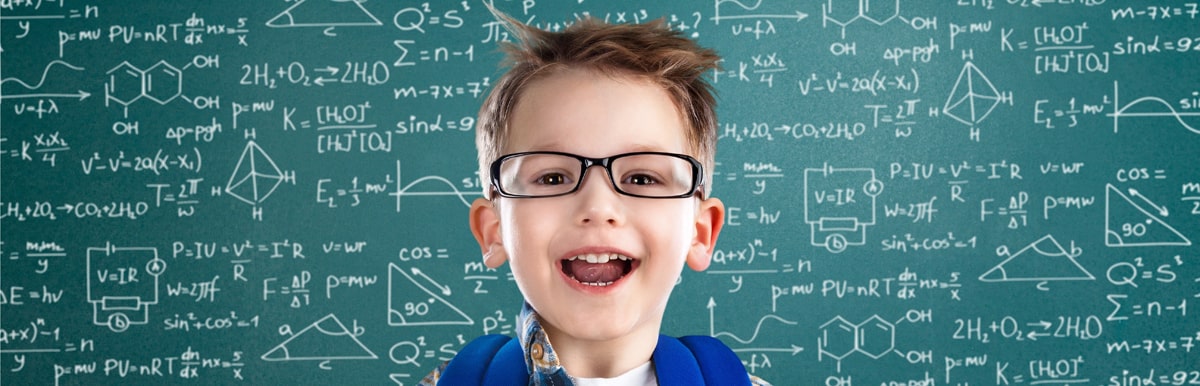 Smiling child wearing glasses and backpack, standing in front of chalkboard filled with maths and science formulas