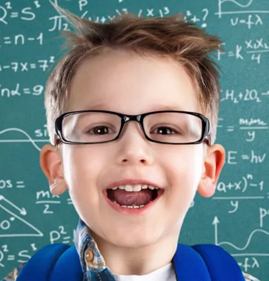 Smiling child wearing glasses and backpack, standing in front of chalkboard filled with maths and science formulas