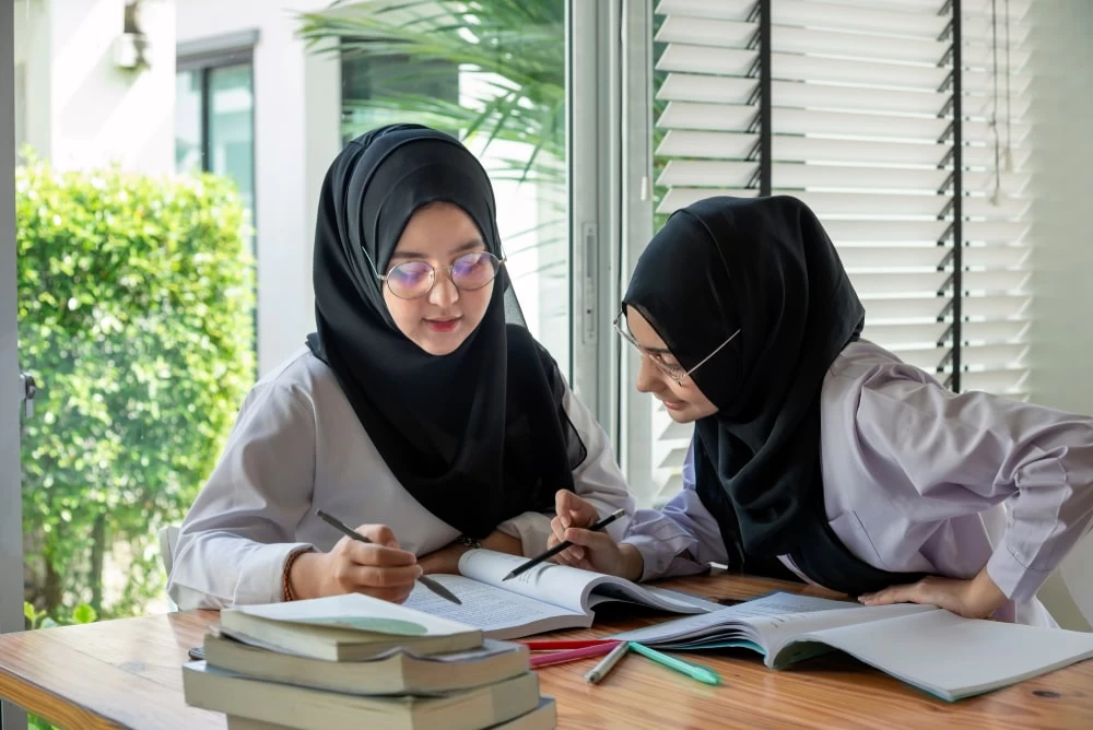 Two female chemistry students studying together from their text books. 