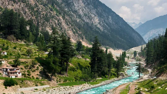 Lush green valley and turquoise river flowing through the mountains of northern Pakistan