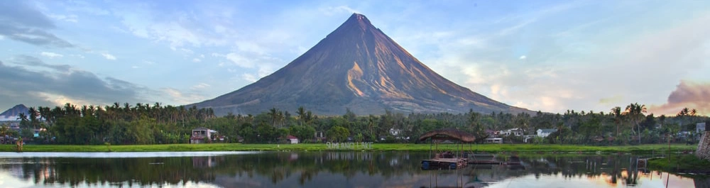 Landscape view of a stand alone Filipino mountain, with a very scenic sky and a green foreground. 
