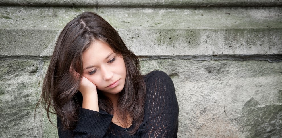 Young girl looking deflated at thought of going to school, demonstrating characteristics of school phobia. 