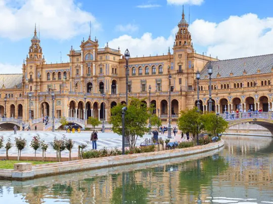 A landscape view of a Spanish city, with a river in the forefront.