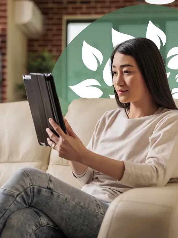 Young woman on cream sofa focused on a tablet in a modern living room setting.