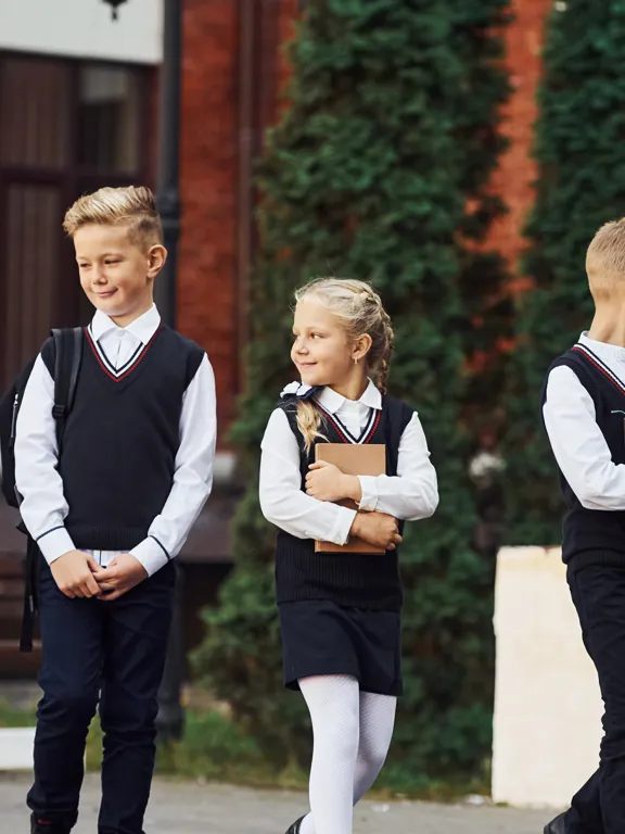 Group of five young students in smart private school uniforms, holding books outdoors, representing the traditional schooling environment that homeschooling serves as a great alternative to.
