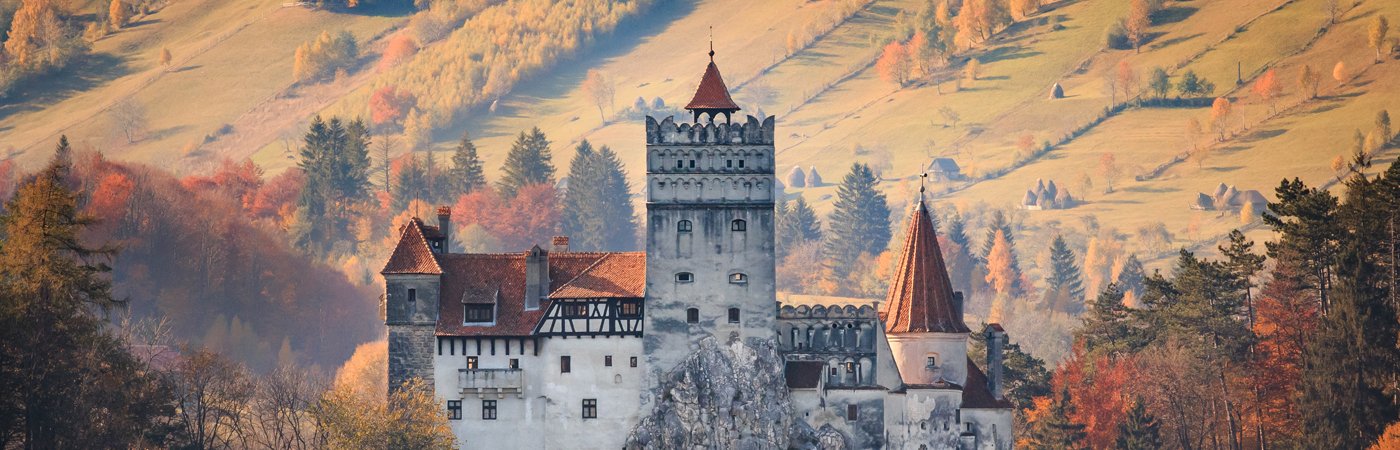 A landscape view of a Romanian castle in the middle of the country side. 
