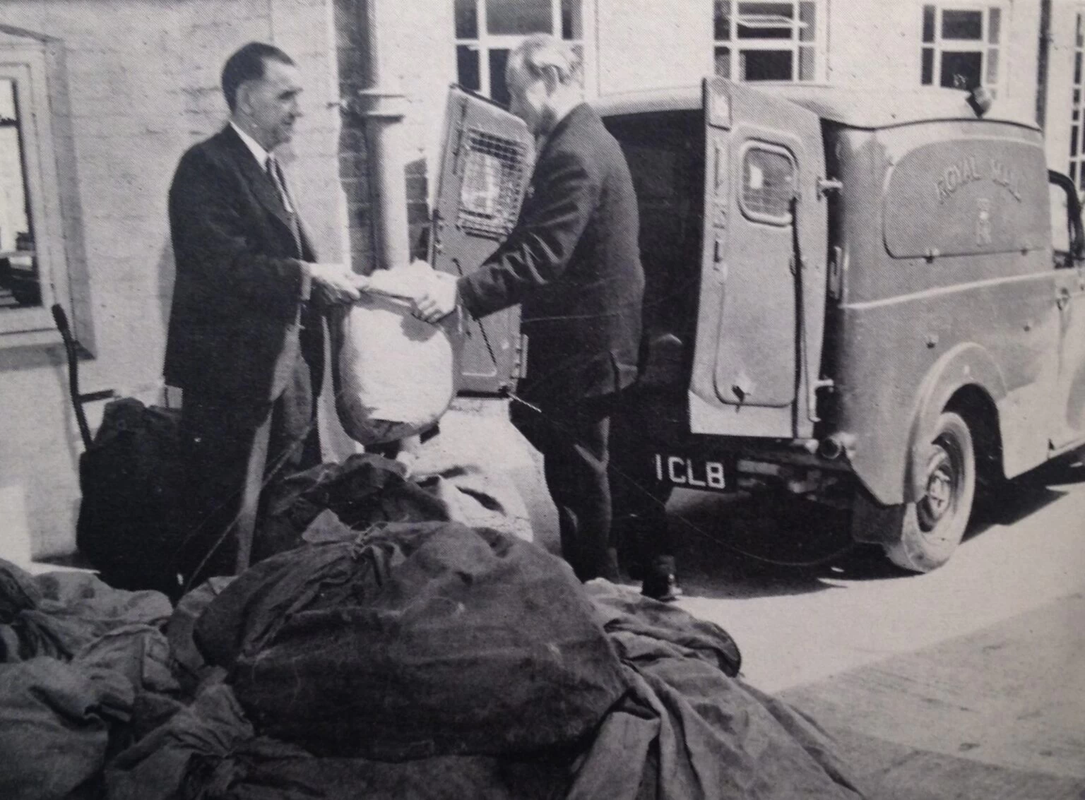 An old photograph of a Wolsey Hall Oxford employee handing correspondence course papers to a postman. The photo is taken from our 1964 prospectus, with the caption: From our 1964 prospectus: “The Post leaves Wolsey Hall. Letters and Lessons leave the College on their journey to all five continents.”
