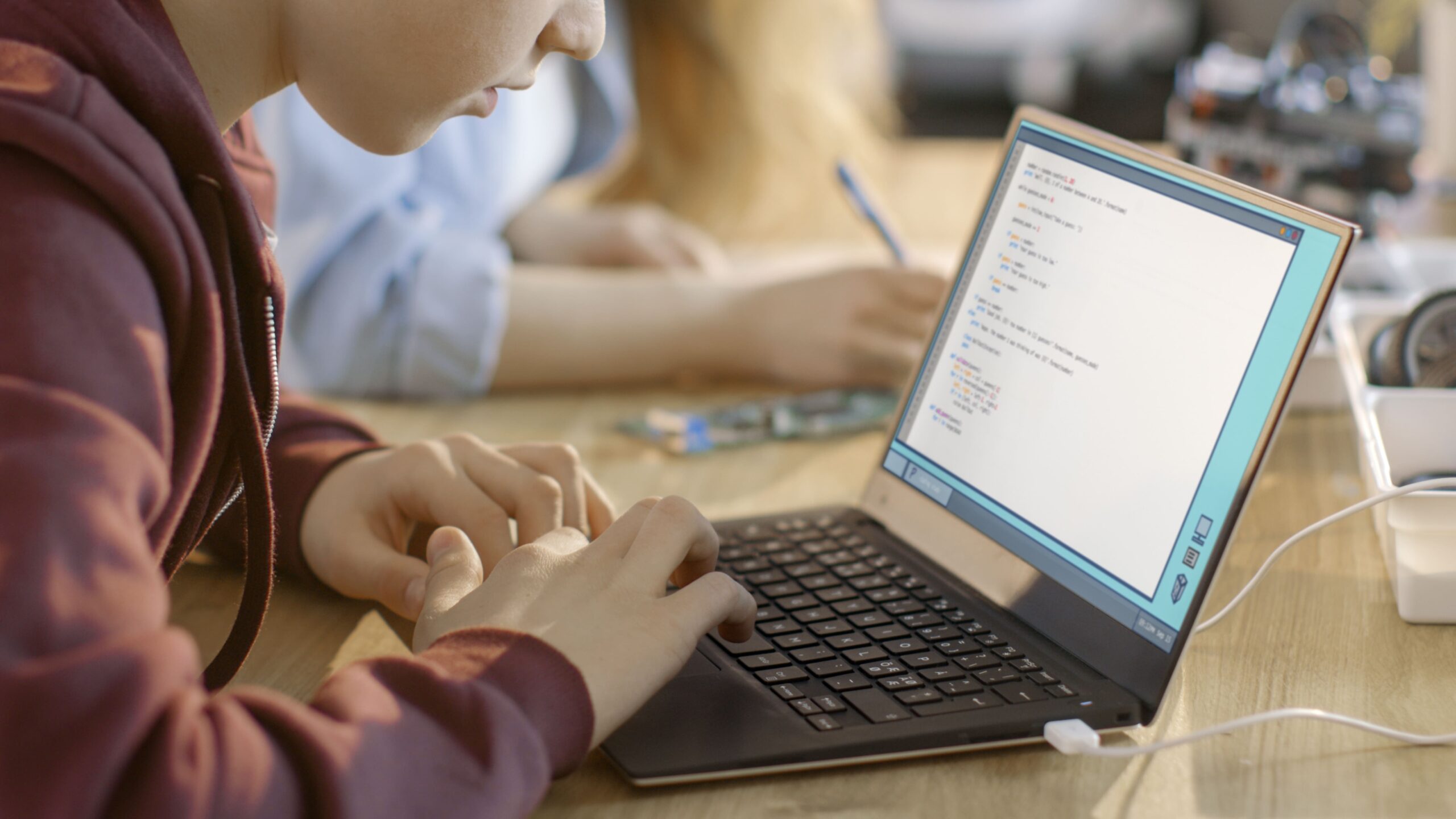 Close-up of a student typing code on a laptop, engaged in programming or computer science learning