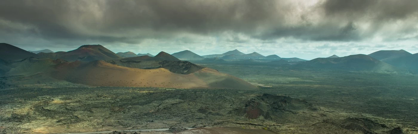 A high view of a vast landscape, with field and mountains, with a storm cloud overhead. 