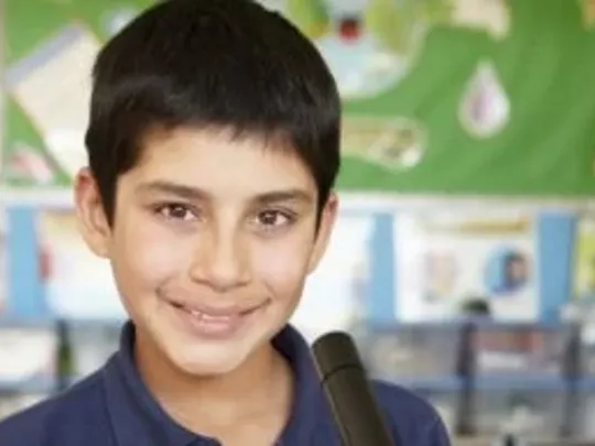 A close-up photograph of a Lower Secondary-age boy with short black hair smiling at the camera.