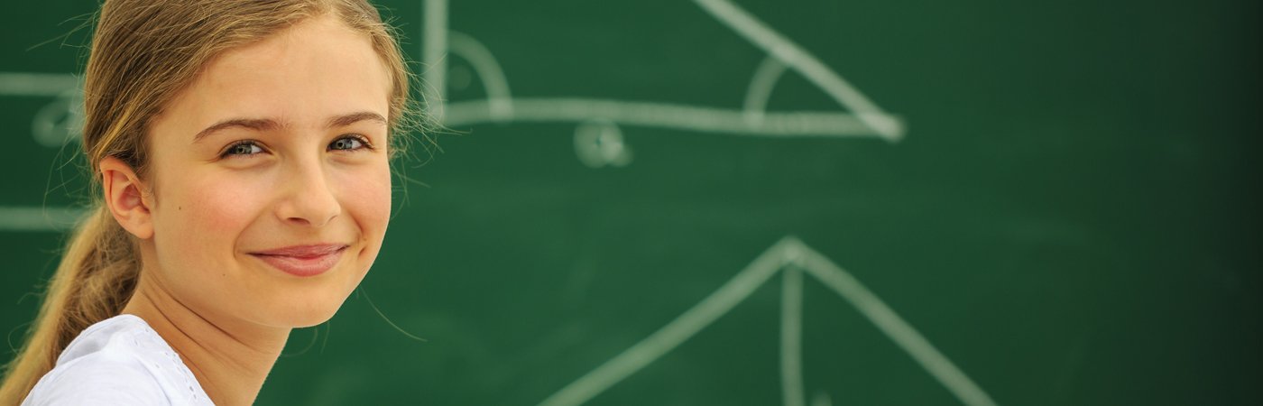 Confident girl standing in front of a green chalkboard with geometric shapes drawn behind her.