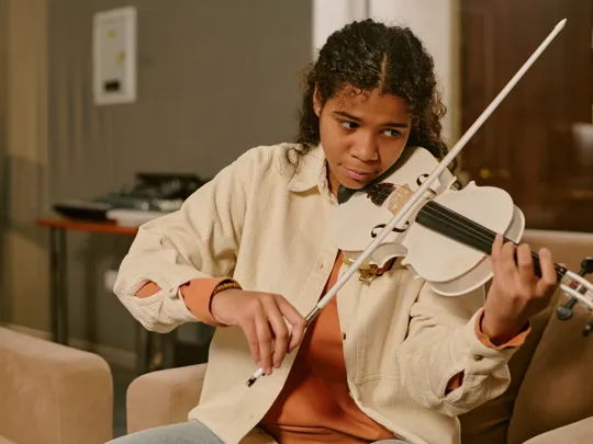 Focused teen practising the violin in a warm indoor space