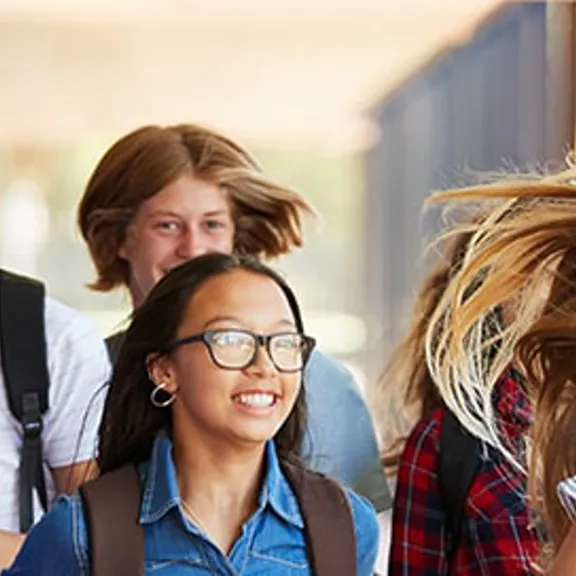 A group of teenagers walking through a hallway.