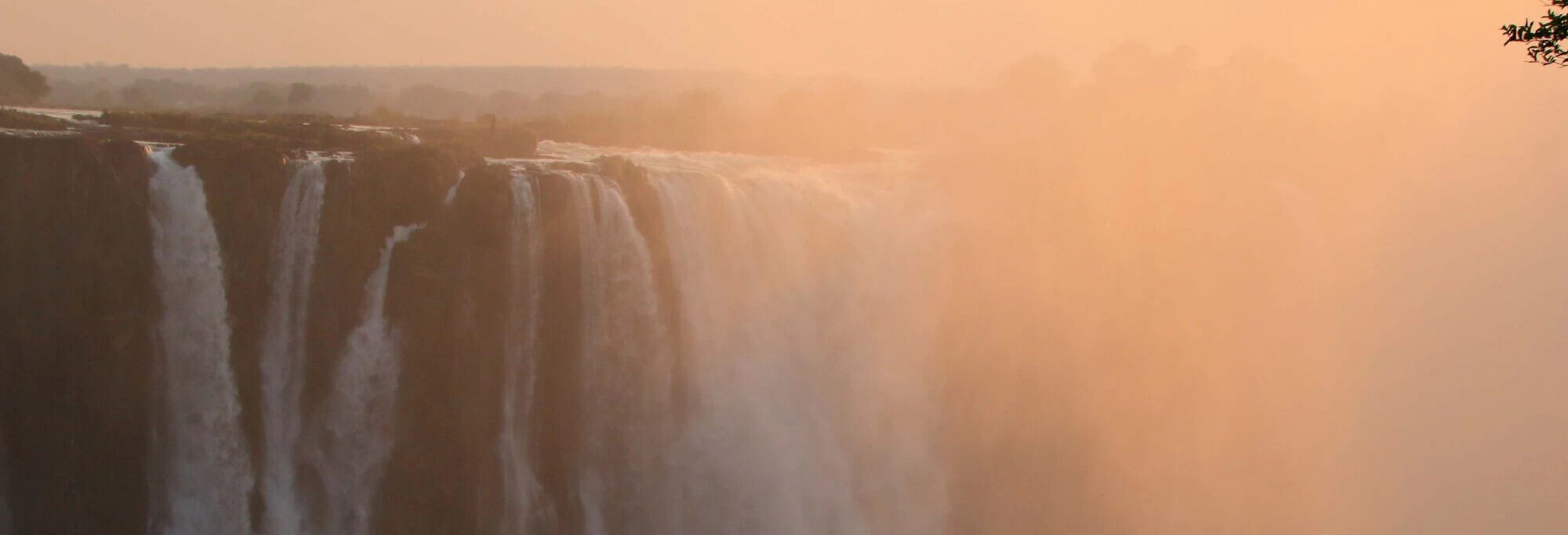 Victoria Falls in Zimbabwe with mist rising at sunset.