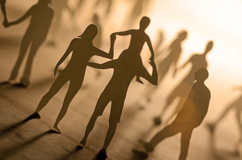 Paper cut-out figures of people in warm light, symbolising family, community and social connection