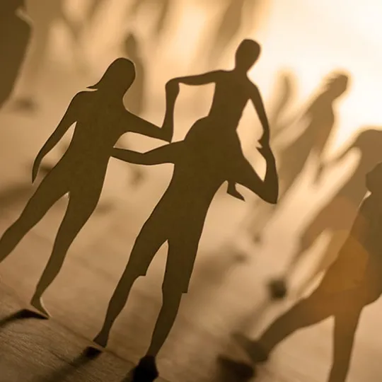 Paper cut-out figures of people in warm light, symbolising family, community and social connection