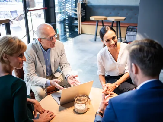 Four professionals having a collaborative meeting in a modern workspace.