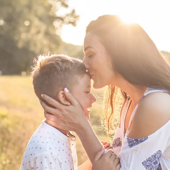 A mother kissing her son on the forehead.