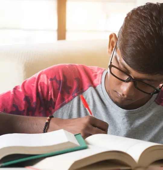 Young male student studying and making notes.