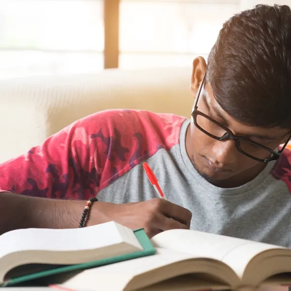 Young male student studying and making notes.
