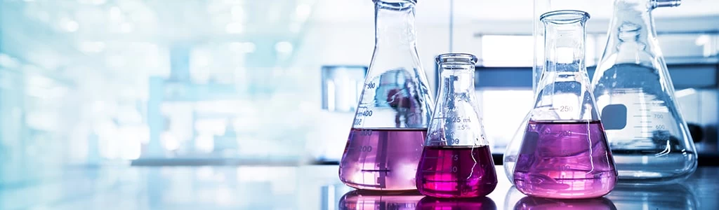 A variety of science beakers with coloured liquid inside. 