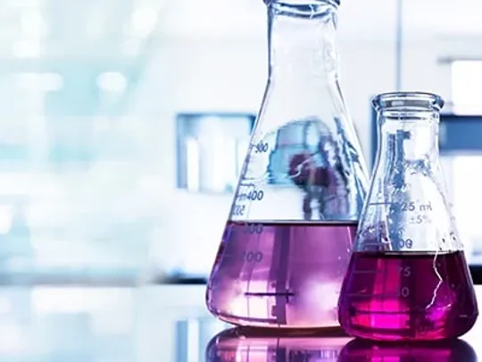 A variety of science beakers with coloured liquid inside.