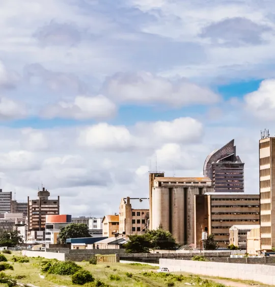 City skyline of Lusaka, Zambia under a cloudy sky with modern and traditional architecture.