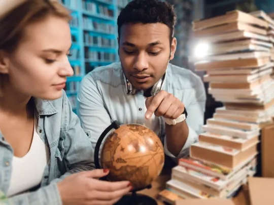 A Level students looking at a globe for their Geography studies.