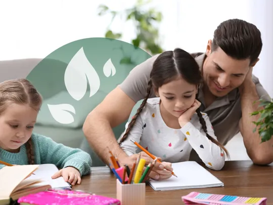 A dad homeschooling his two young daughters at a desk.