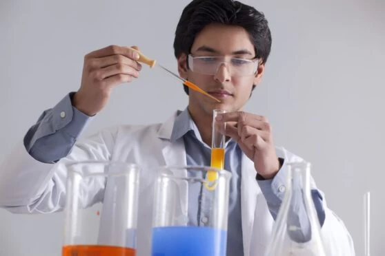 A male science student undertaking a science experiment. 